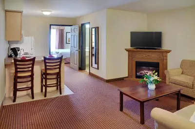 a living room with a fireplace and a table and chairs at Pomeroy Inn and Suites Chetwynd in Chetwynd