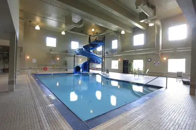 a large swimming pool with a slide in a building at Pomeroy Inn and Suites Chetwynd in Chetwynd