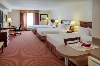 a hotel room with two beds and a table with wine glasses at Pomeroy Inn & Suites Fort St. John in Fort Saint John