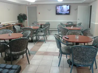 a restaurant with tables and chairs and a tv on the wall at Stampeder Inn in Ponoka