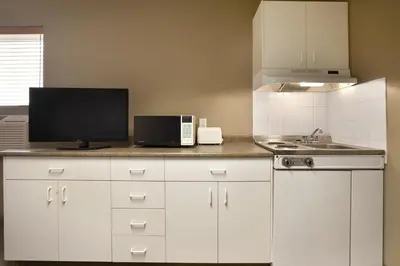 a kitchen with white cabinets and a sink and a microwave at Central Suite Hotel in Lloydminster