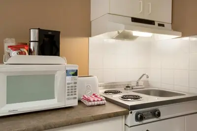 a kitchen with a microwave and a sink at Central Suite Hotel in Lloydminster