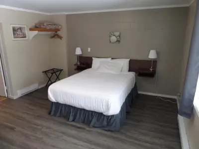 a bedroom with a large bed with white sheets and pillows at Ray Lyn Motel in Trail