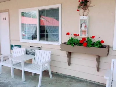 a window with two chairs and a flower box with red flowers at Red Roof Motor Inn in Hope