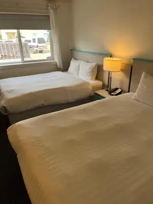 two beds in a hotel room with a window at Revelstoke Lodge in Revelstoke
