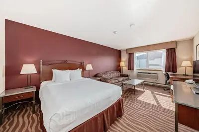a hotel room with a large bed and a couch at Invermere Inn & Suites in Invermere