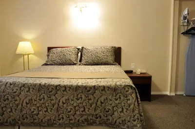 a bedroom with a bed and a table with a lamp at Rosedale Motel in Summerland