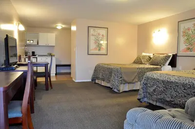 a hotel room with two beds and a kitchen at Rosedale Motel in Summerland
