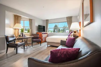 a hotel room with a couch and a bedroom at Coast Parksville Hotel in Parksville