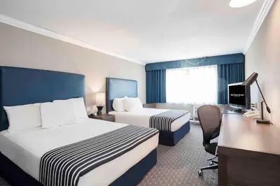 a hotel room with two beds and a desk at Sandman Inn Blue River in Blue River