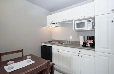 a kitchen with white cabinets and a table and a microwave at Sandman Inn Cache Creek in Cache Creek