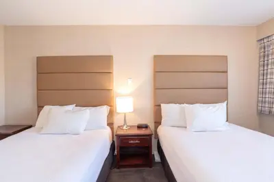 a hotel room with two beds and a table with a lamp at Sandman Hotel Cranbrook in Cranbrook