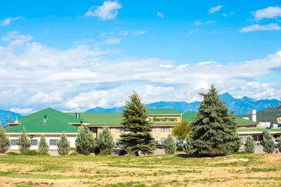 a building with trees in front of it at Sandman Hotel Cranbrook in Cranbrook
