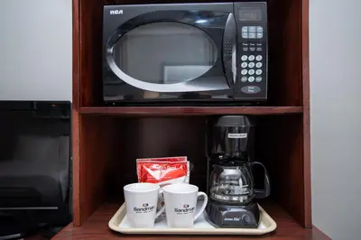 a microwave and two coffee cups on a shelf at Sandman Inn Kamloops in Kamloops