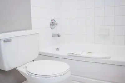 a white bathroom with a toilet and a bath tub at Sandman Inn Kamloops in Kamloops