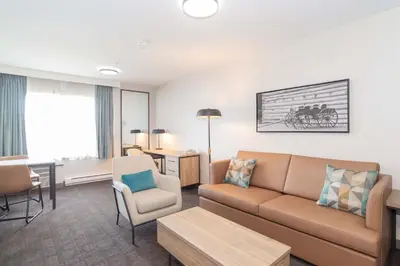 a living room with a couch and chairs in a room at Sandman Hotel Quesnel in Quesnel