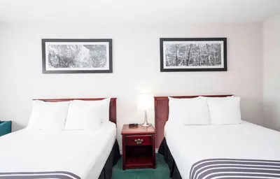 a hotel room with two beds and a night stand at Sandman Inn Smithers in Smithers