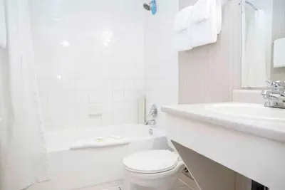a white bathroom with a toilet and a sink at Sandman Inn Smithers in Smithers