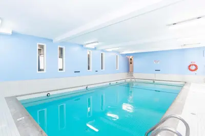 a swimming pool in a building with blue walls at Sandman Hotel Terrace in Terrace