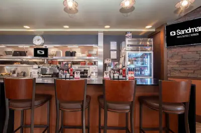 a bar with five chairs in a restaurant at Sandman Hotel Vernon in Vernon