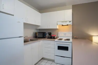 a kitchen with white cabinets and a white stove top oven at Sandman Hotel & Suites Williams Lake in Williams Lake