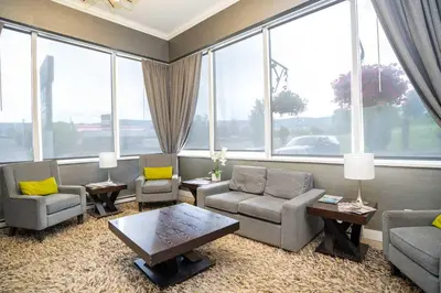 a living room with couches and chairs and large windows at Sandman Hotel & Suites Williams Lake in Williams Lake