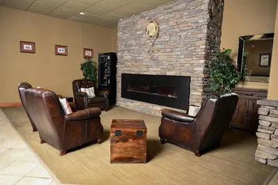 a living room with leather chairs and a fireplace at Quality Hotel & Conference Centre in Peace River