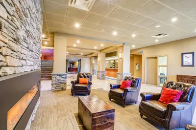 a lobby with chairs and a stone wall at Quality Hotel & Conference Centre in Peace River