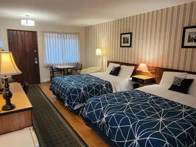 a hotel room with two beds and a table at Schooner Motel in Tofino