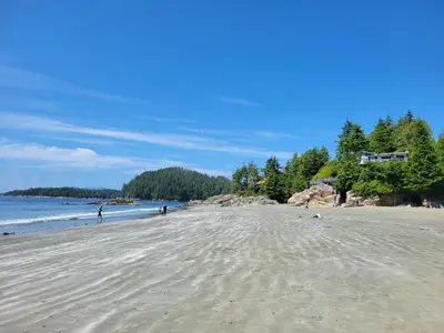 a beach with people walking on the sand at Schooner Motel in Tofino