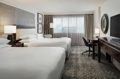 a hotel room with two beds and a desk at Sheraton Cavalier Calgary Hotel in Calgary