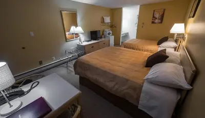 a hotel room with two beds and a desk at Westwood Motel 100 Mile House in One Hundred Mile House