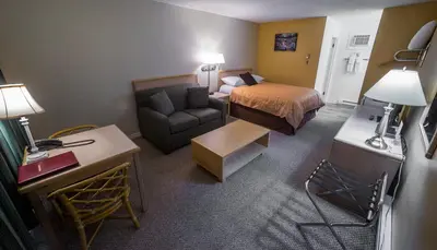 a small hotel room with a bed and a couch at Westwood Motel 100 Mile House in One Hundred Mile House