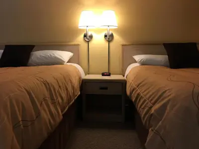 a hotel room with two beds and a table with a lamp at Westwood Motel 100 Mile House in One Hundred Mile House