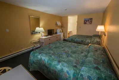 a hotel room with two beds and a desk at Westwood Motel 100 Mile House in One Hundred Mile House