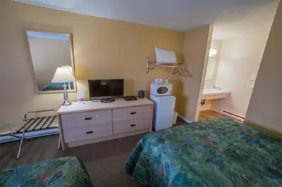 a hotel room with a bedroom with a bed and a tv at Westwood Motel 100 Mile House in One Hundred Mile House