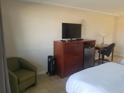 a bedroom with a bed and a tv and a chair at Super 8 by Wyndham Smoky Lake in Smoky Lake