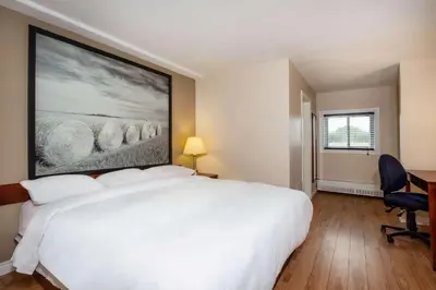 a bedroom with a white bed with a painting on the wall at Super 8 by Wyndham Smoky Lake in Smoky Lake