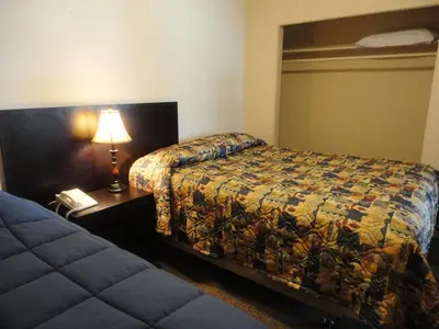 a bedroom with a bed and a lamp and a phone at Stratford Motel in Whitehorse