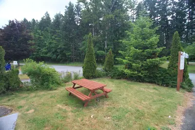 a wooden bench sitting in the grass in a park at Sunset Motel & Trailer Park, Incorporated in Port Alberni