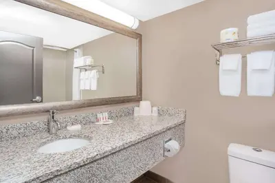 a bathroom with a sink and a mirror and a toilet at Super 8 by Wyndham Athabasca AB in Athabasca