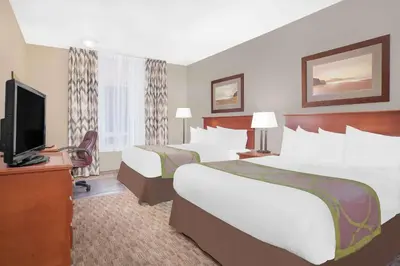 a hotel room with two beds and a flat screen tv at Super 8 by Wyndham Athabasca AB in Athabasca