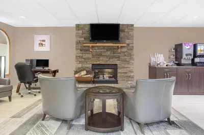 a living room with two chairs and a fireplace at Super 8 by Wyndham Athabasca AB in Athabasca