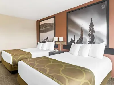 a hotel room with two beds and a large screen at Super 8 by Wyndham Meadow Lake in Meadow Lake