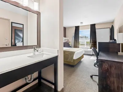 a hotel room with a sink and a bed at Super 8 by Wyndham Meadow Lake in Meadow Lake