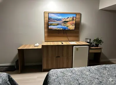 a room with two beds and a flat screen tv at Quesnel Inn in Quesnel