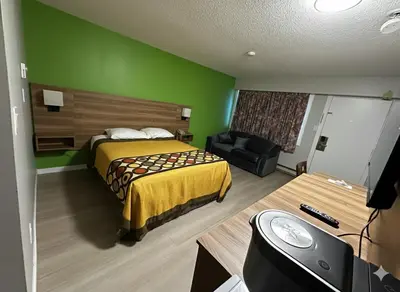 a hotel room with a bed and a green wall at Quesnel Inn in Quesnel