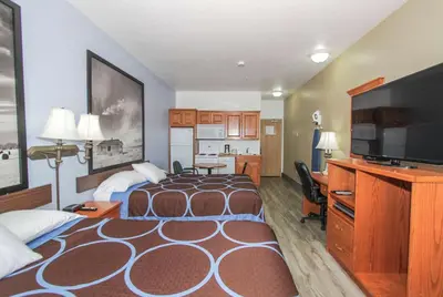 a hotel room with two beds and a flat screen tv at Super 8 by Wyndham Three Hills AB in Three Hills