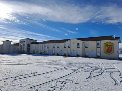 a building in the snow with footprints in the snow at Super 8 by Wyndham Three Hills AB in Three Hills