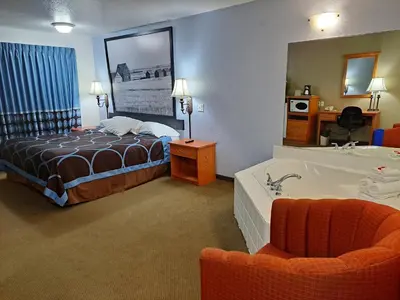 a hotel room with a bed and a bath tub at Super 8 by Wyndham Three Hills AB in Three Hills